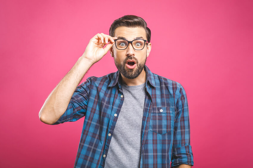 Handsome man with glasses looking at the camera surprised