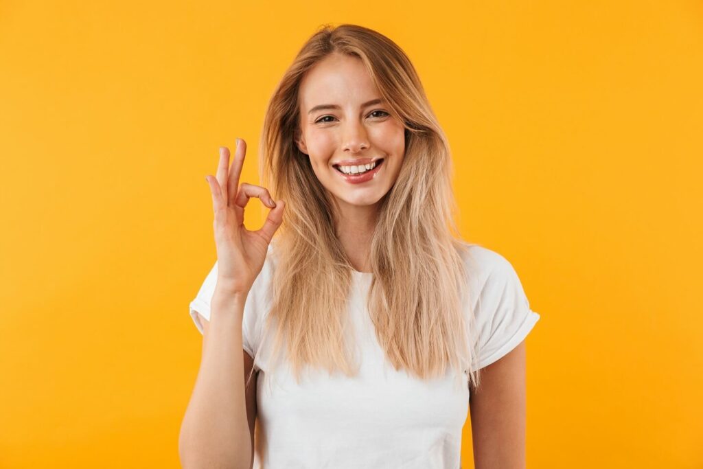 Very attractive deaf girl smiling in the camera and making a hand sign