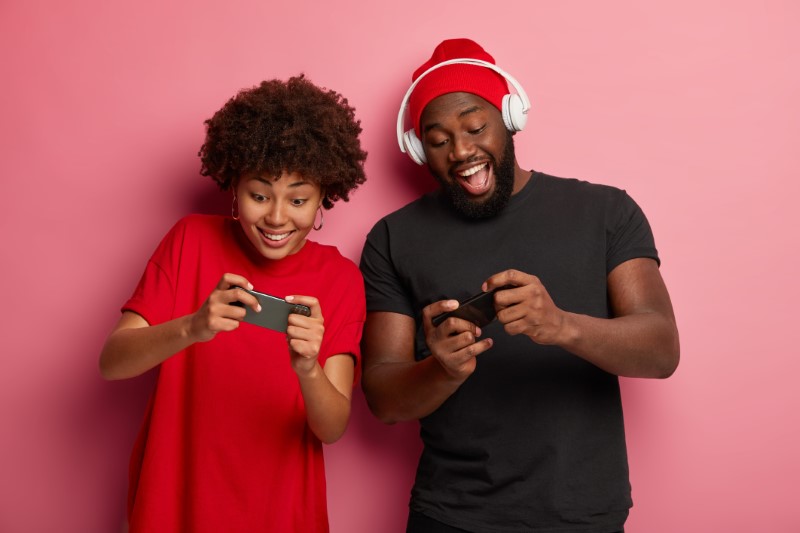 Geek couple challenging each other in a smartphone game