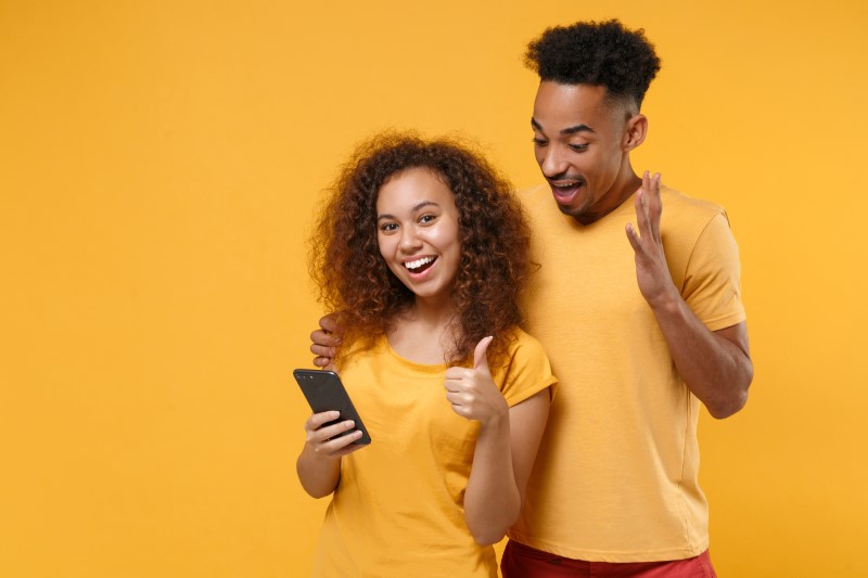 Girl dating on her smartphone, single man cheering for her match