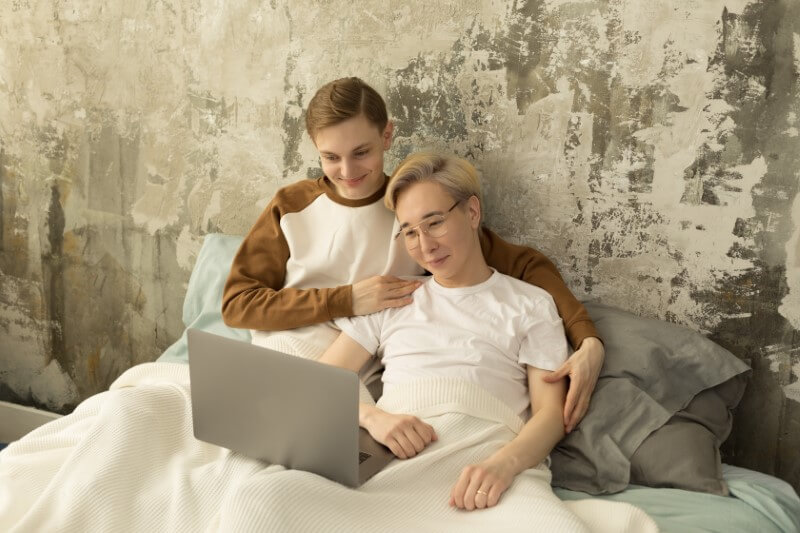 Gay couple watch a movie in bed