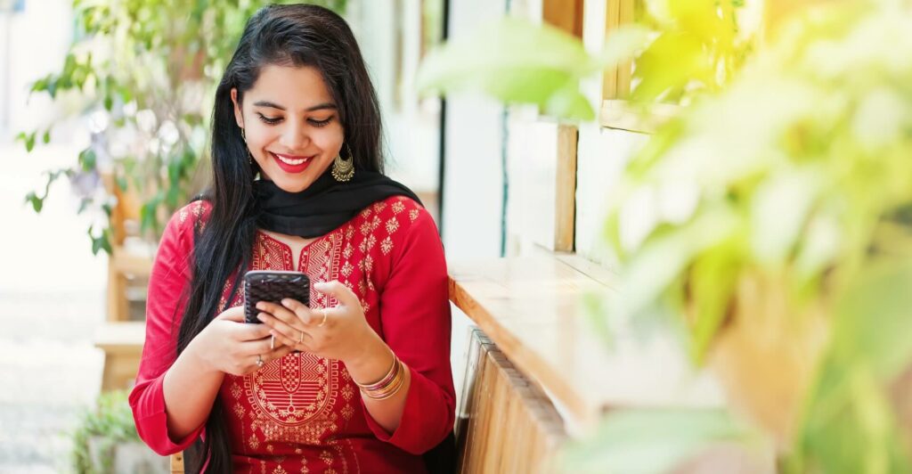 Stunning indian girl smiles at her smartphone