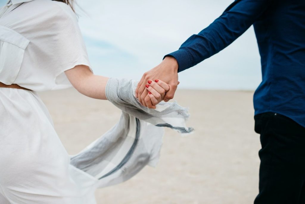 Couple holding hands running on beach