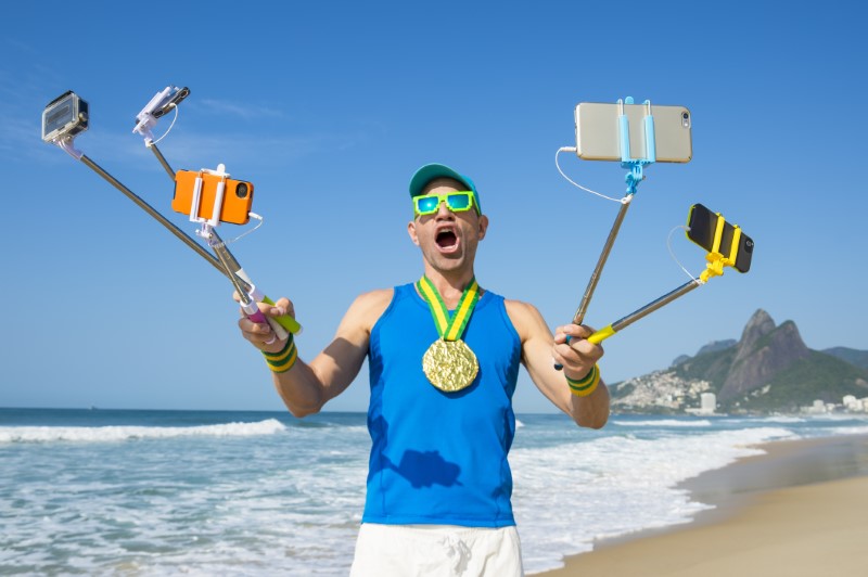 Crazy guy takes funny selfie with several selfie sticks on a beach