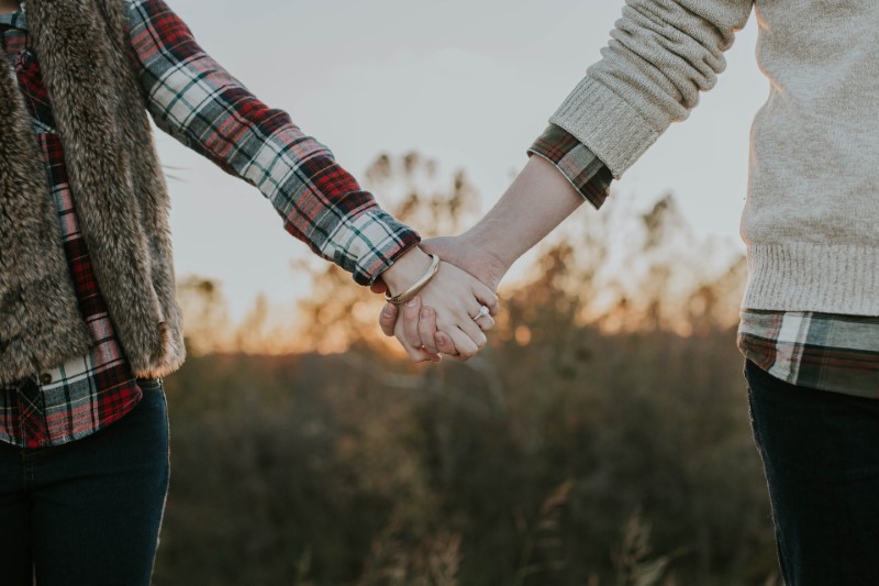 Two people holding hands outside