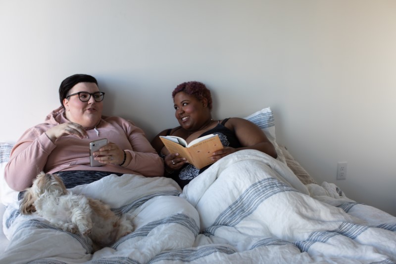 Two plus size girlfriends cuddled up in bed